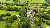 Luftaufnahme der malerischen All Saints Church, umgeben von üppigen Feldern und einer ruhigen Landschaft, Devon, Vereinigtes Königreich.