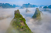 Luftaufnahme einer Aussichtsterrasse auf dem Berggipfel mit Blick auf die Berglandschaft von Guilin bei Sonnenaufgang mit tief hängenden Wolken, Guangxi, China.