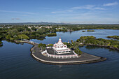 Luftaufnahme eines makellosen weißen Tempelkomplexes mit rot gemauertem Sockel, umgeben von tiefblauem Wasser und üppigem Grün, Central Flacq, Flacq District, Mauritius.
