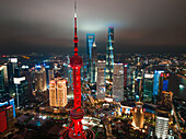 Schanghai, China - 21. Juni 2025: Luftaufnahme des Oriental Pearl Tower, der sich rot von der nächtlichen Skyline abhebt, ein Leuchtturm inmitten der beleuchteten Wolkenkratzer.
