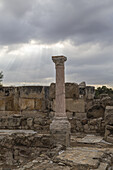 View of a solitary column stands amidst the weathered ruins, bathed in ethereal light filtering through the overcast sky, Salamis Harabeleri, Harabeleri Salamis Yolu, Cipro.