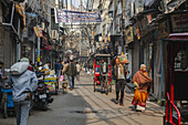 New Delhi, India - 24 June 2025: View of a bustling street scene with pedestrians, rickshaws, and overhead wires creating a maze-like canopy above a lively market area.