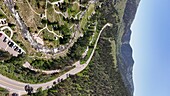 Aerial view of the winding Big Thompson Road cutting through lush forests and rocky terrain, showcasing nature's raw beauty, Loveland, Colorado, United States.