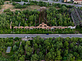 Aerial view of ruins of a once-grand structure now entwined with verdant overgrowth, a ghostly monument beside the road, Brescia, Lombardia, Italy.