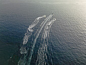 Aerial view of jet skis carving white wakes through the deep blue sea, creating a dynamic pattern of movement and contrast, Comino, Gajnsielem, Malta.