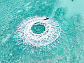 Aerial view of a jet ski creating swirling patterns in the turquoise water, a dance of motion and color against the tranquil sea, Gulhi, Kaafu Atoll, Maldives.