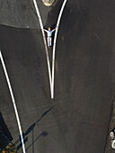 Aerial view of a man lying on the dark asphalt road, between bright white lines, creating a striking contrast, Alessandria, Italy.