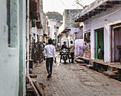 Agra, India - 24 June 2025: View of a narrow street lined with aged buildings and shops, where a motorbike idles amidst the dusky light.