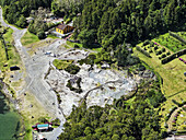 Luftaufnahme von dampfenden Vulkanschloten und mineralhaltigen Becken, die sich von der leuchtend grünen Vegetation abheben - ein Zeugnis der Kraft und Schönheit der Natur, Furnas, Azoren, Portugal.