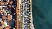 Luftaufnahme von Terrakotta-Dächern und der türkisfarbenen Adria entlang der Riva-Promenade, Split, Gespanschaft Split-Dalmatien, Kroatien.
