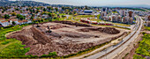 Luftaufnahme von Baggern, die Muster in die Erde graben, vor dem Hintergrund moderner Gebäude, Afula, Nordbezirk, Israel.