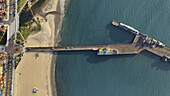 Luftaufnahme der Stearns Wharf, die sich in den weiten blauen Ozean erstreckt und mit dem goldenen Sand des Strandes kontrastiert, Santa Barbara, Kalifornien, Vereinigte Staaten.