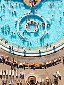 Aerial view of the bright turquoise waters of the Szechenyi Thermal Baths shimmer under the sunlight, a vibrant hub of activity and relaxation, Budapest, Hungary.