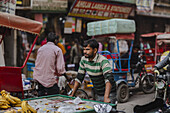 New Delhi, India - 24 June 2025: View of a man cycling through the bustling street, with vibrant colors of shops and goods creating a lively atmosphere.