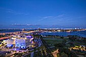 Aerial view of the Adrienne Arsht Center glows against the twilight, Biscayne Bay reflecting the city lights, a vibrant tapestry of urban life, Miami, Florida, United States.