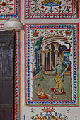 Bikaner, India - 24 June 2025: View of an ornate wall painting depicting a deity with vibrant colors and intricate details, framed by decorative borders.