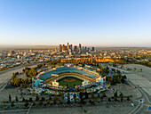Aerial view of Dodger Stadium bathed in the warm glow of sunrise with the city skyline in the distance, Los Angeles, California, United States.