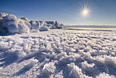 View of a vast, icy expanse under a radiant sun, where intricate frost patterns meet snowy formations, creating a mesmerizing winter landscape, Baikal, Irkutsk Oblast, Russia.