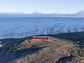 Luftaufnahme einer einsamen roten Struktur, die sich entschlossen von der weiten, eisigen Landschaft der Seymour-Insel abhebt, Seymour-Insel, Antarktis.
