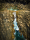 Luftaufnahme von zerklüfteten Klippen, die das türkisfarbene Meer umarmen, wo schäumende weiße Wellen gegen die Felsen schlagen, Sugarloaf Rock, Westaustralien, Australien.