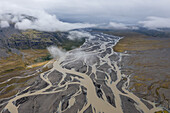 Luftaufnahme von verzweigten Flüssen, die sich durch eine karge Landschaft unter einem wolkenverhangenen Himmel schlängeln, eine Symphonie aus Grau und Braun, Selfoss, Sveitarf?lagi? ?rborg, Island.