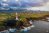 Luftaufnahme des markanten rot-weißen Albion-Leuchtturms, der sich vor der zerklüfteten Küste erhebt, wo das Land auf den weiten Ozean trifft, Mauritius.