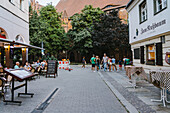 Berlin, Germany - 27 August 2019: View of the vibrant, bustling street scene unfolds with 'Zum Nußbaum' restaurant nestled among lush trees and historic architecture.