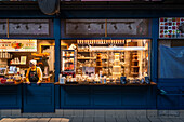 Budapest, Hungary - 07 October 2025: View of a cozy chocolate shop, where warm interior lights illuminate a tempting display of sweet treats, contrasting with the cool blue exterior.