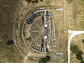 Aerial view of the ancient Roman Theater's weathered stones and symmetrical design, a testament to history amidst the sun-drenched landscape, Gubbio, Perugia Province, Italy.