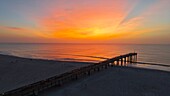 Luftaufnahme des langen Piers von Saint Johns County, der sich unter einem strahlenden Sonnenaufgangshimmel in den Ozean erstreckt, Saint Augustine Beach, Florida, Vereinigte Staaten.