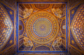 Samarkand, Uzbekistan - 05 May 2024: View of the Gur-e-Amir mausoleum's intricate ceiling, where golden patterns meet azure depths, creating a mesmerizing dance of light and shadow overhead.