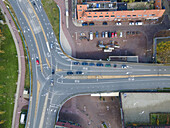Aerial view of sharp road intersection with brick buildings and parked cars, the scene is a mix of gray roads and green foliage, Amsterdam, North Holland, Netherlands.