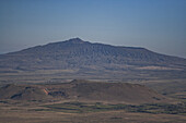 Blick auf die majestätische Bergkette und kleinere Hügel vor dem klaren Himmel, wobei Braun- und Grüntöne nahtlos ineinander übergehen, Longonot, Bezirk Nakuru.