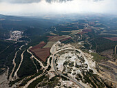 Aerial view of the landscape where roads meander through the rugged terrain, revealing a tapestry of textures and tones, with the earth's raw beauty contrasting against the sky, Vavdos, Greece.