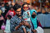 Bogura, Bangladesch - 03. November 2023: Blick auf eine Familie, das Kind mit roter Sonnenbrille, inmitten der pulsierenden, geschäftigen Menge, ein Teppich aus Farben und Leben.