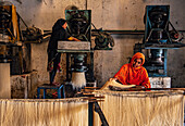 Bogura, Bangladesh - 23 March 2023: View of women meticulously crafting and arranging fine, silky strands in a bustling factory, bathed in warm, industrial light.
