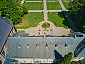 Aerial view of the grand Chateau St. Gerlach's tiled roof contrasting with the vibrant green geometric gardens, a tranquil scene, Valkenburg, Limburg, Netherlands.