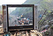 Chittagong, Bangladesh - 15 November 2018: View of cattle grazing amidst discarded waste, framed by the stark contrast of an old television set.