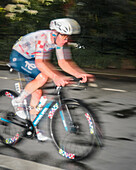 Paris, France - 27 July 2025: View of a determined cyclist of the Tour de France 2025 in motion, racing through the city streets, a blur of speed and vibrant colors against the dark asphalt.