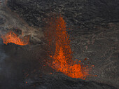 Luftaufnahme von geschmolzener Lava, die die zerklüfteten, dunklen Hänge hinunterfließt, ein feuriges Schauspiel vor der kargen Landschaft, Grindavik, Region Südliche Halbinsel, Island.