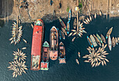 Luftaufnahme von Booten am Flussufer, deren leuchtende Farben mit dem dunklen Wasser kontrastieren, ein Tanz von Handel und Leben, Dhaka, Dhaka District, Bangladesch.