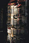 Porto, Portugal - 17 June 2022: View of weathered buildings casting long shadows, their facades a tapestry of faded yellows, reds and whites, capturing the essence of old European charm.