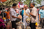 Bogura, Bangladesh - 03 November 2023: View of a marketplace scene unfolds with vibrant colors as men examine traditional drums, the textures of wood and cloth contrasting under a bright day.