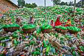 Bogura, Bangladesh - 26 July 2018: View of women amidst a stark landscape of discarded plastic bottles, sorting through the waste with colorful garments.