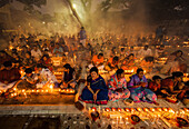 Narayanganj, Bangladesh - 11 June 2018: View of a multitude of people gathered, softly lit by candles, their faces serene in the warm glow, creating a tranquil and spiritual atmosphere.