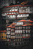Porto, Portugal - 17. Juni 2022: Blick auf die gestapelten Gebäude des Ribeira-Viertels mit ihren leuchtend roten Dächern, die kaskadenartig den Hang hinunterfallen und einen reizvollen Kontrast zu den verwitterten Fassaden bilden.