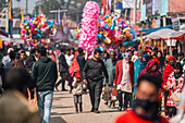 Bogura, Bangladesh - 03 November 2023: View of a bustling street market scene with vibrant pink balloons contrasting against the earthy tones of stalls and pedestrians.