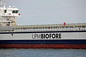 Ostsee, Deutschland - 11. Juli 2023: Blick auf das Frachtschiff UPM BIOFORE, das durch das ruhige Wasser gleitet. Sein Rumpf bildet einen starken Kontrast aus tiefem Blau und leuchtendem Rot vor dem blassen Himmel.