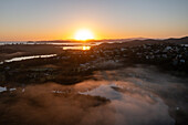 Aerial view of the golden sunrise casts a warm glow over the misty landscape and waterways, reflecting the serene beauty of the region, Whangarei, Northland Region, New Zealand.