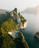 Aerial view of towering limestone cliffs meet the turquoise waters of Maya Bay, fringed by verdant jungle, creating a stunning contrast, Krabi, Mueang Krabi District, Thailand.